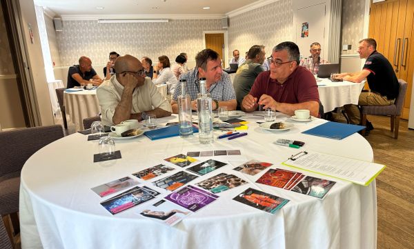 Engineering academics working in a strategy session to design inclsuion into their courses. the foreground contains postcard images of engineering failures.